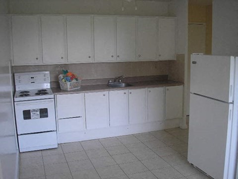 a white kitchen with a sink and a refrigerator